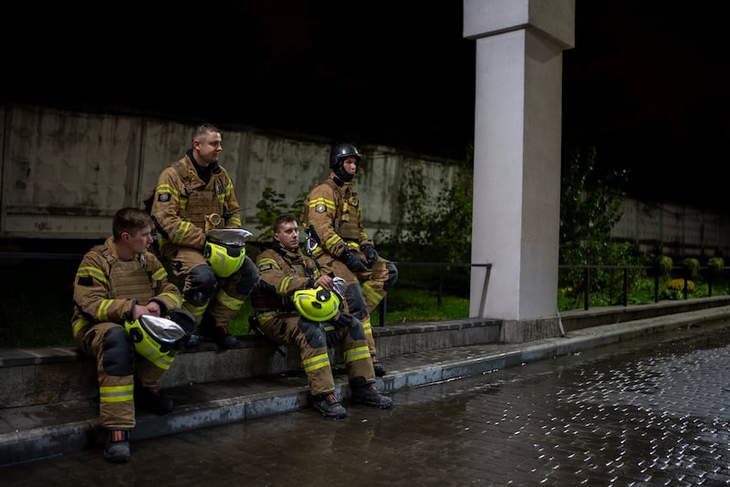 Firefighters rest on a curb during after responding to a Russian drone attack (AP Photo/Alex Babenko)