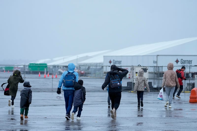 Immigrants run in the rain towards the tents at migrant housing location at Floyd Bennett Field in New York (Mary Altaffer/AP)