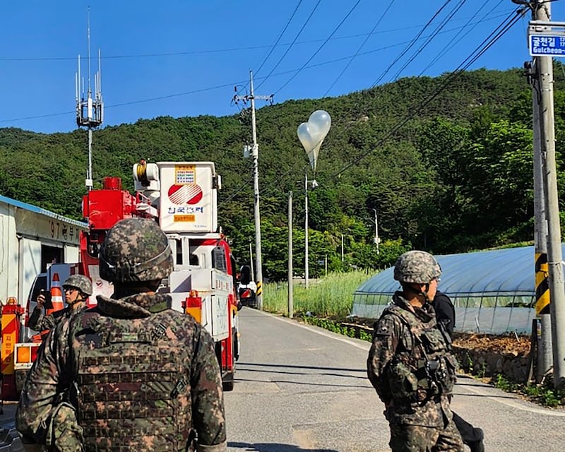 Balloons filled with rubbish hang on electric wires in Muju as South Korean army soldiers stand guard in Muju (Jeonbuk Fire Headquarters/AP)