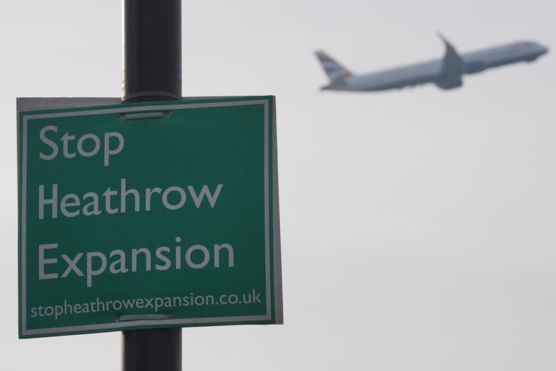 A plane flies past a ‘Stop Heathrow Expansion’ sign near the airport