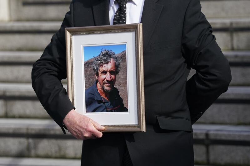 A man holds a photograph of Charlie Bird at a service at Mansion House