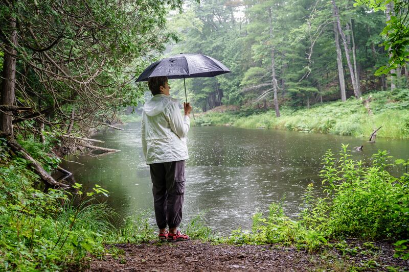 Woman with umbrella standing on a river bank in the rain