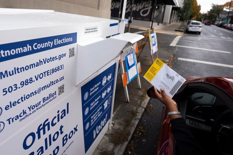 A voter drops off a ballot for the 2024 election in a newly installed drop box at the Multnomah County Elections Division office in Portland, Oregon, after the pervious drop box was damaged (Jenny Kane/AP)