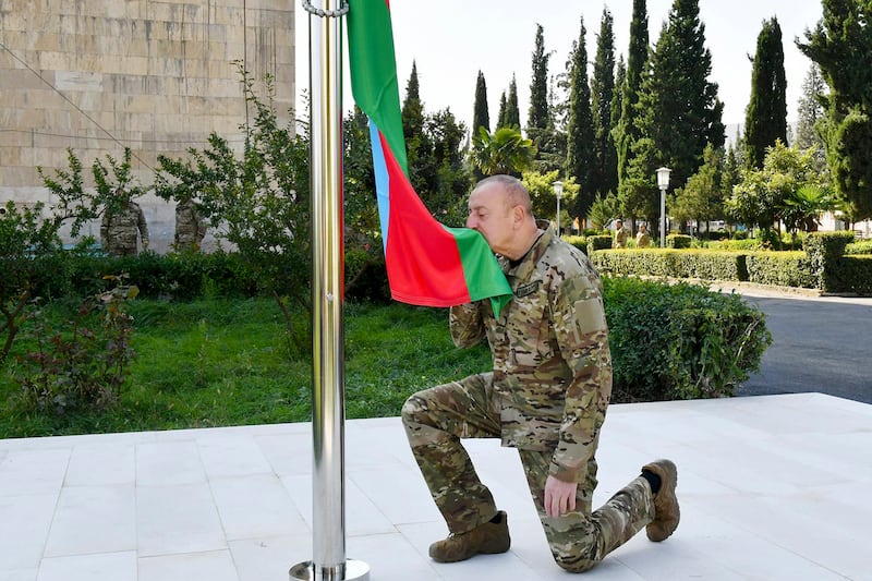 President Ilham Aliyev kisses a national flag in the city of Aghdara, which was once under Armenian control (Azerbaijani Presidential Press Office/AP)