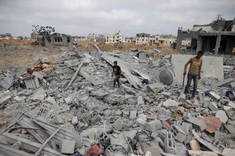 Palestinians look at the destruction after an Israeli airstrike in Khan Younis (AP)