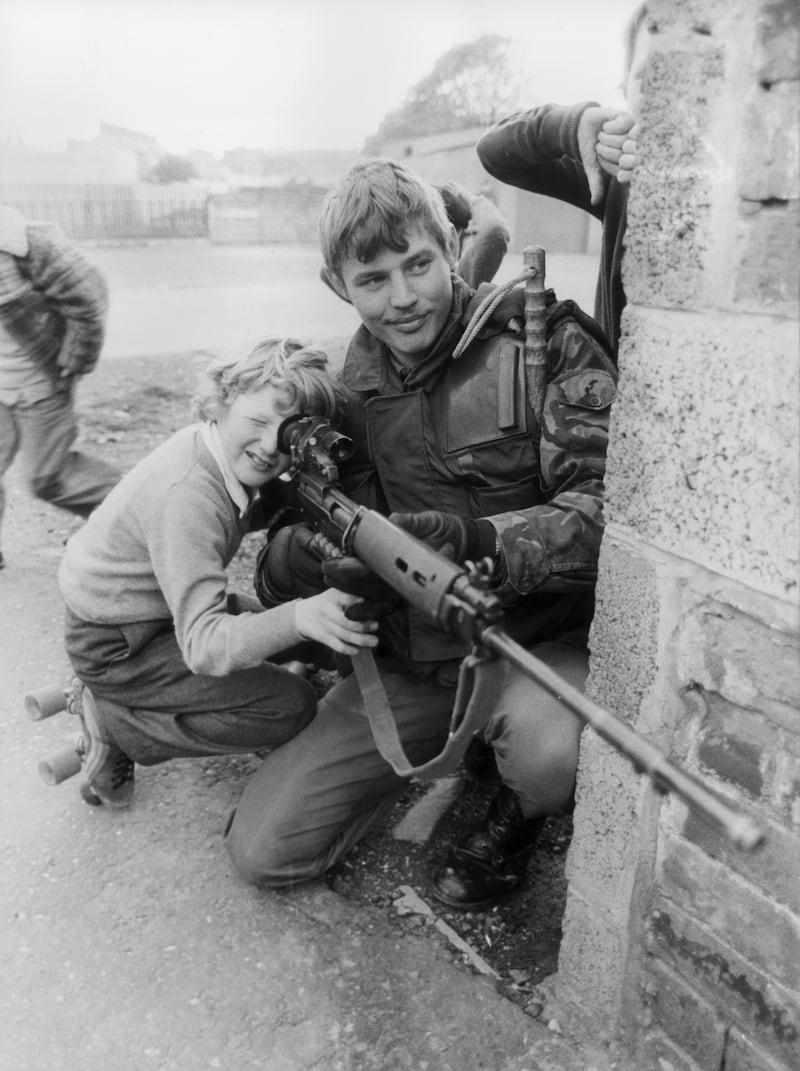 A British soldier lets a young boy look through the sights of his rifle in Belfast in 1981. Picture: Central Press/Getty Images