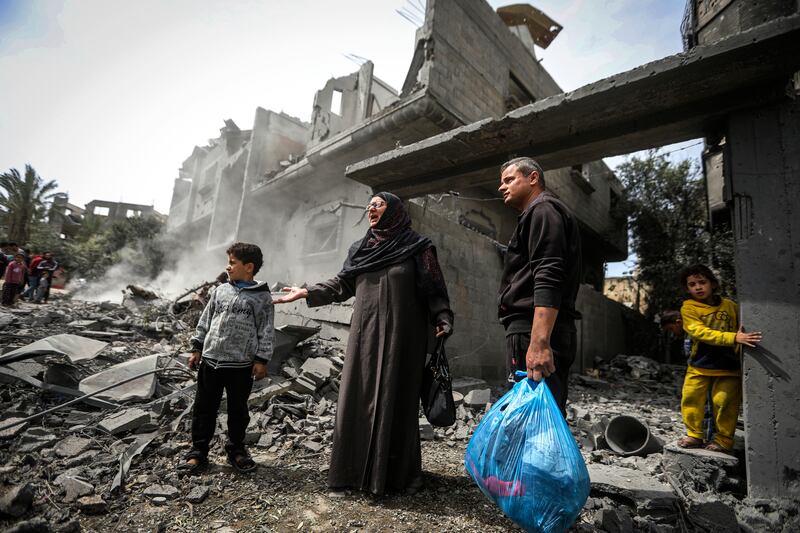 Palestinians collect their belongings from the rubble of a residential building (Ismael Abu Dayyah/AP)
