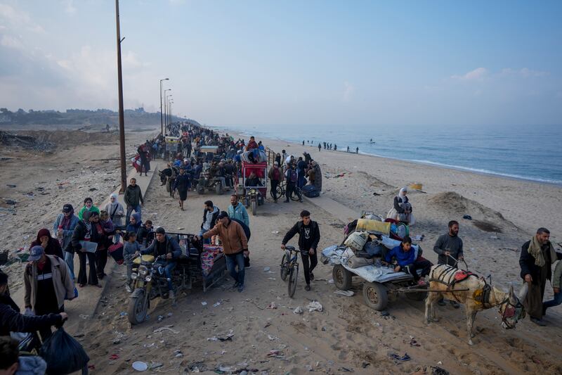 Displaced Palestinians walk on a road in central Gaza to return to their homes following the Israel-Hamas ceasefire deal (Abdel Kareem Hana/AP)