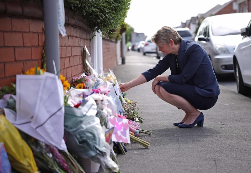 Home Secretary Yvette Cooper reads messages left on flowers near the scene