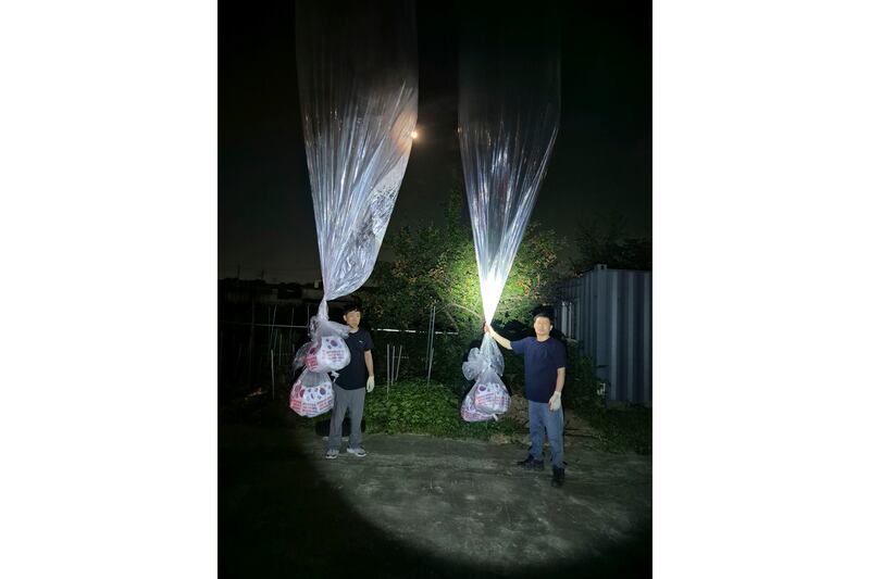 North Korean defector Park Sang-hak, left, and a member of Fighters For A Free North Korea hold balloons bearing anti-North Korean propaganda leaflets near the border with North Korea (Fighters For A Free North Korea/AP)