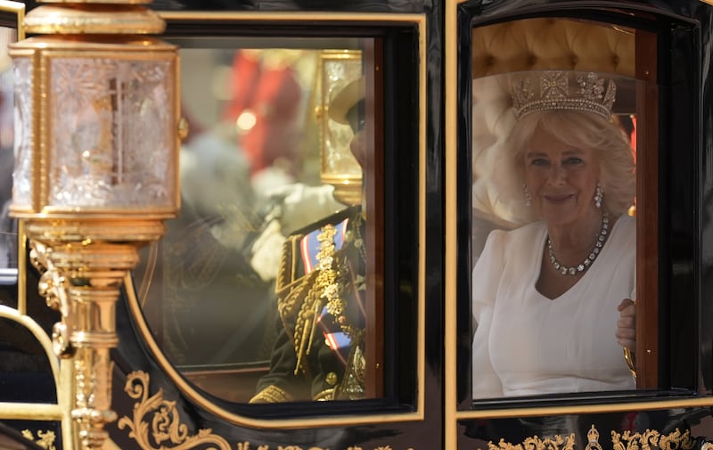 The Queen smiles as she leaves the Palace in procession to the House of Lords