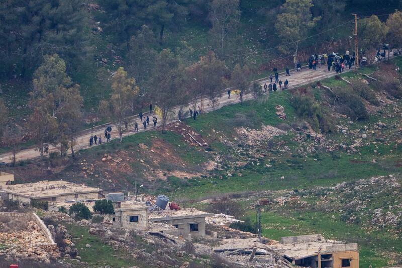 A group of people waves flags as they approach the outskirts of the southern Lebanese village of Al-Aadaissah (Ariel Schalit/AP)