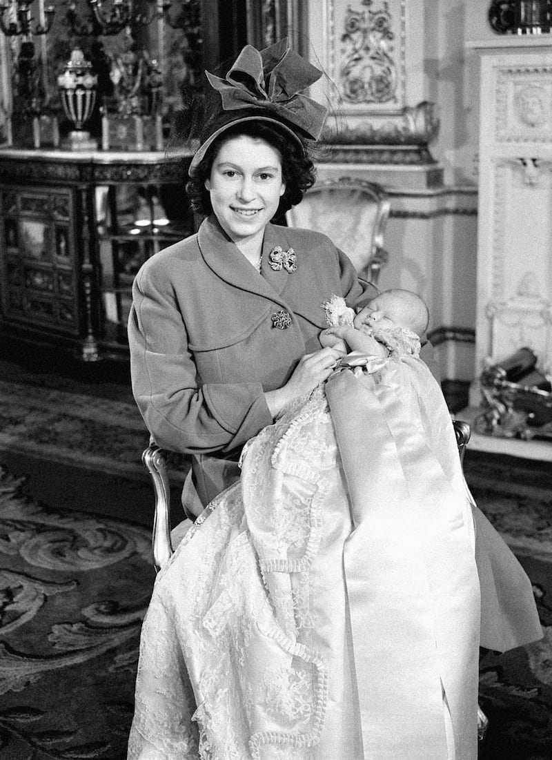 Princess Elizabeth holds her one-month-old baby son, Prince Charles, after his christening ceremony at Buckingham Palace in 1948