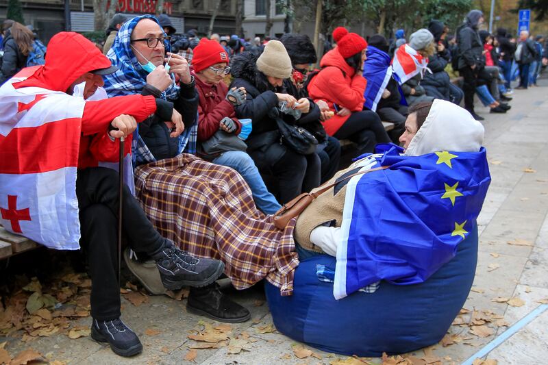 Protesters with EU and Georgian national flags rest during a rally to demand new parliamentary elections (Shakh Aivazov/AP)