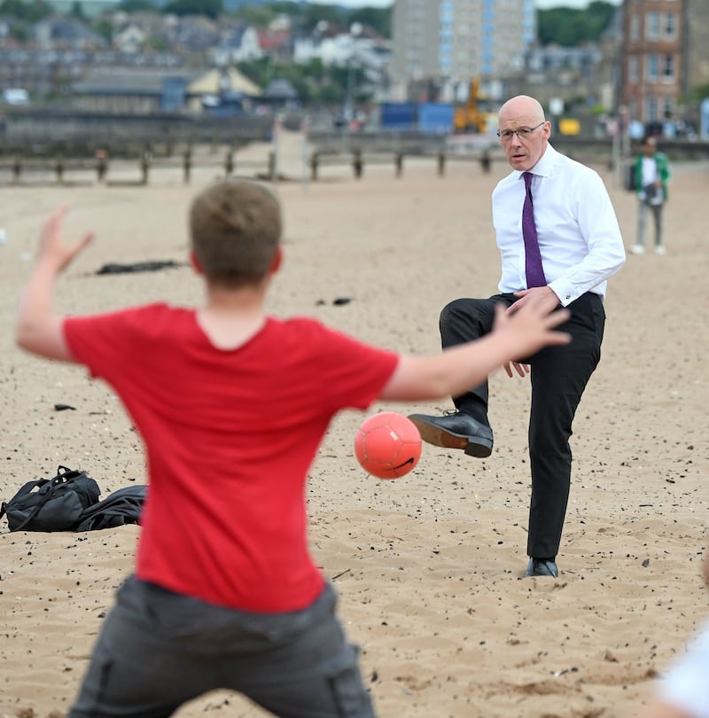 SNP leader John Swinney plays football with local children at Portobello beach and promenade