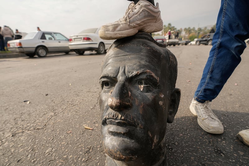 An opposition fighter steps on a broken bust of the late Syrian president Hafez Assad in Damascus following the downfall of the government of his son Bashar (Hussein Malla/AP)