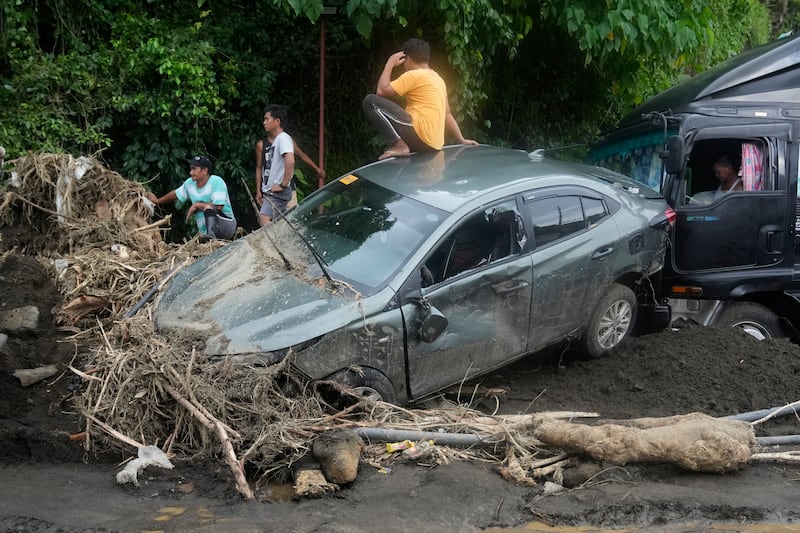 A man sits on a damaged car after a landslide triggered by Tropical Storm Trami in Talisay, Batangas province (AP Photo/Aaron Favila)