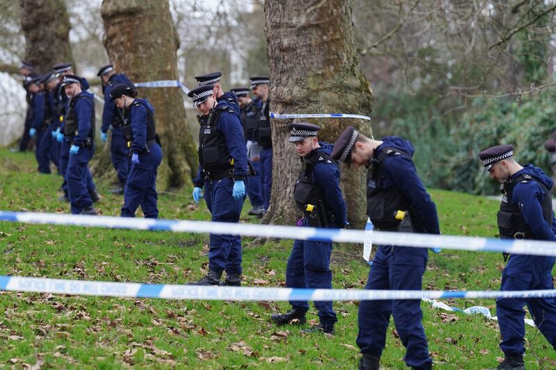 Police officers conduct a fingertip search of the scene