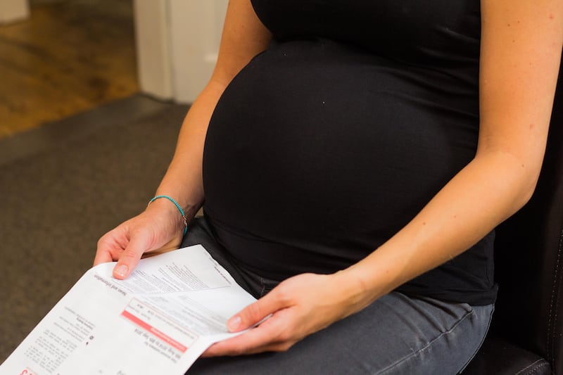 Close up photo of pregnant woman looking at a bill