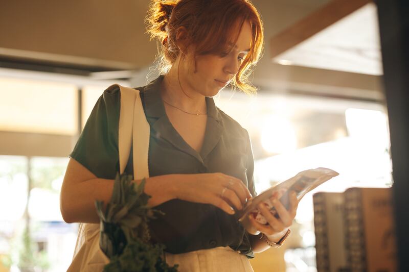 A woman in a supermarket reading a food label