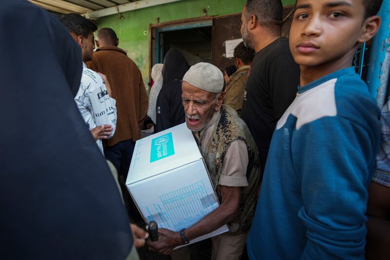 Palestinians receive aid distributed by UNRWA (Abdel Kareem Hana/AP)