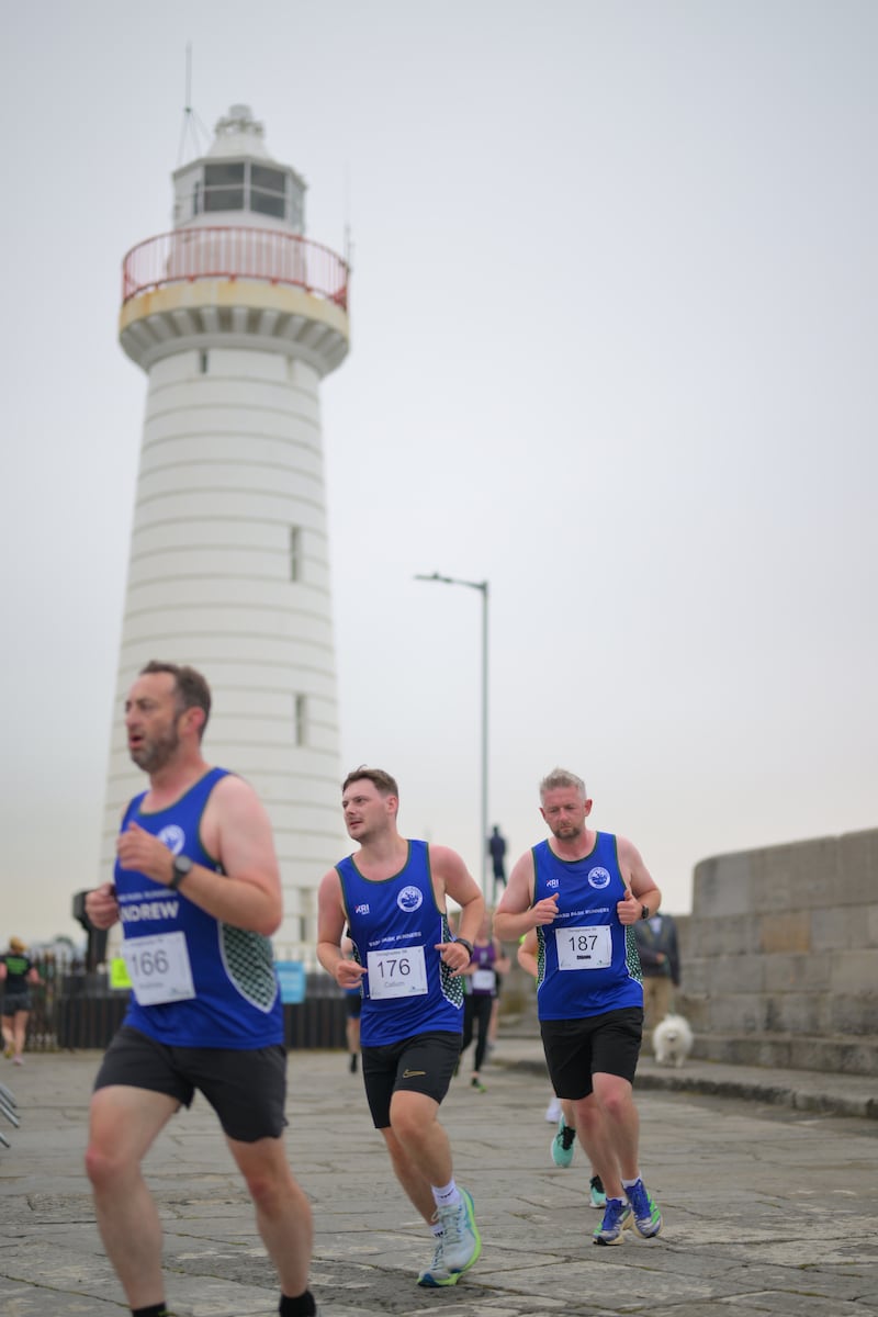 Group of runners in 5k race in front of white lighthouse