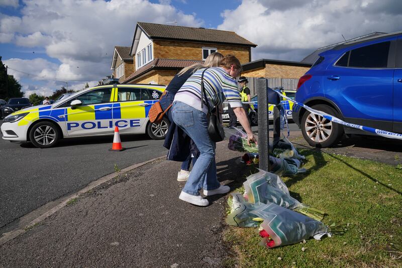 People deliver floral tributes near to the scene in Ashlyn Close, Bushey, Hertfordshire