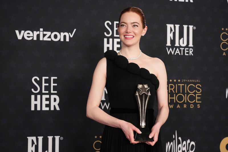 Emma Stone poses in the press room with the award for best actress for Poor Things (Jordan Strauss/Invision/AP)