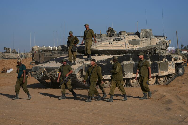 Israeli soldiers walk in a staging area for their tanks near the Gaza border in southern Israel (AP)