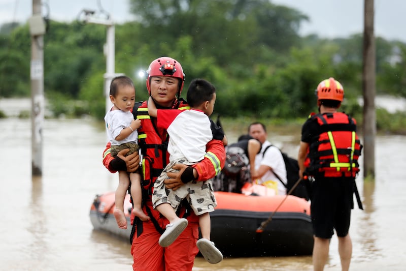 A rescuer evacuates children trapped by floodwater in Jingtang village in southern China’s Hunan province (Chinatopix/AP)