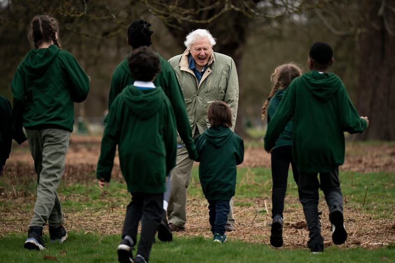 Sir David Attenborough with schoolchildren as he plants the tree in Richmond Park