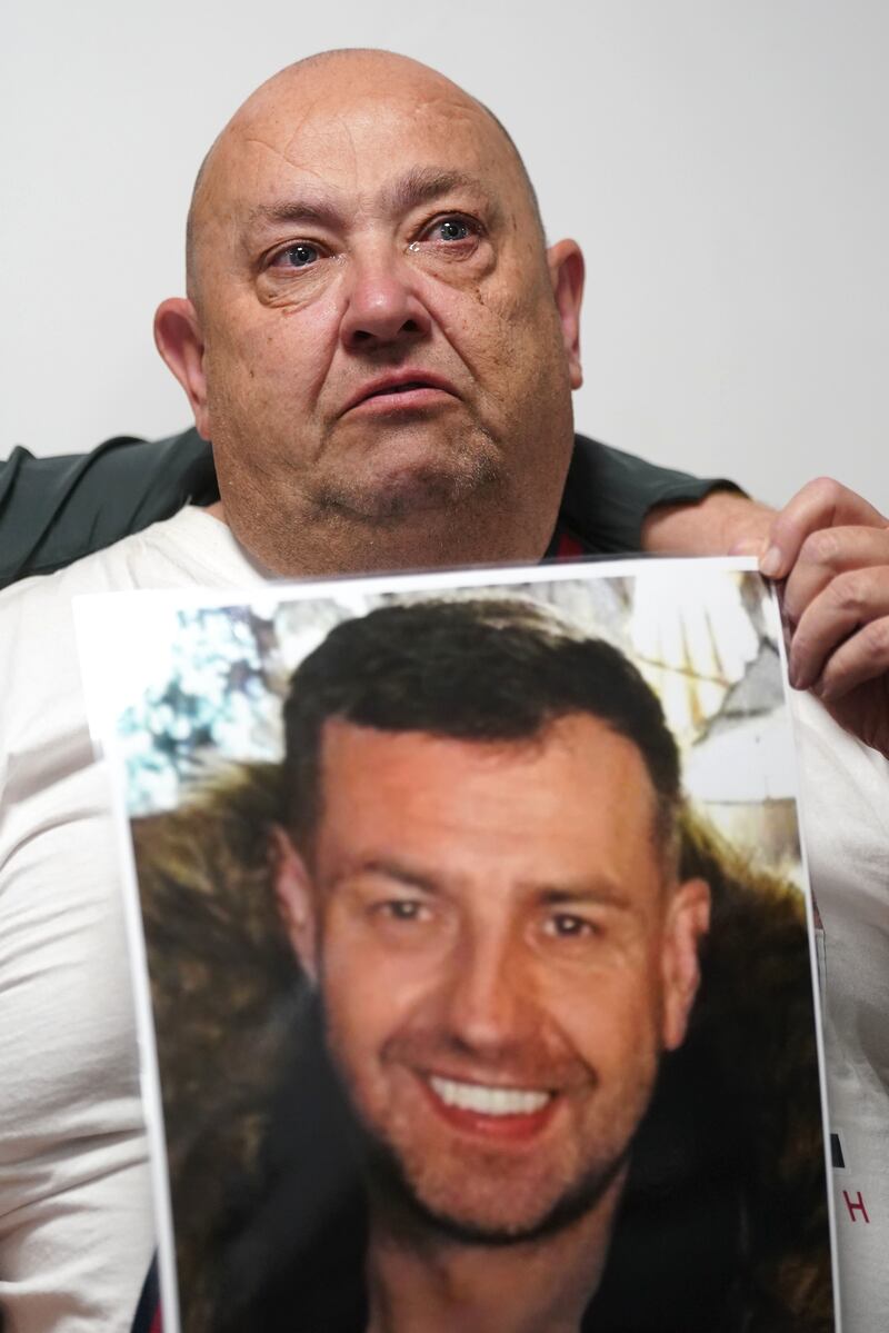 Billy, the father of John George, holds a photo of his son after returning to Belfast following the search