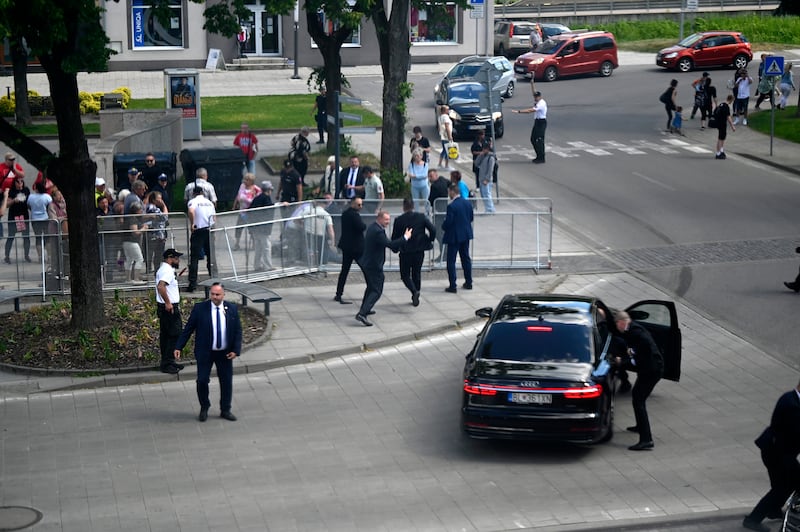 Bodyguards take Slovak Prime Minister Robert Fico in a car from the scene after he was shot and injured in Handlova, Slovakia (Radovan Stoklasa/AP)