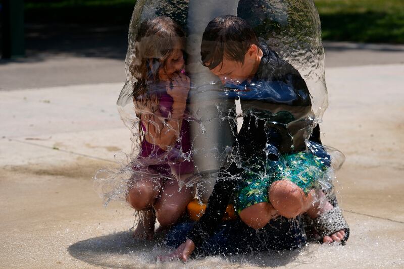Two children play under a water sprinkler at Broad Ripple Park in Indianapolis (Darron Cummings/AP)