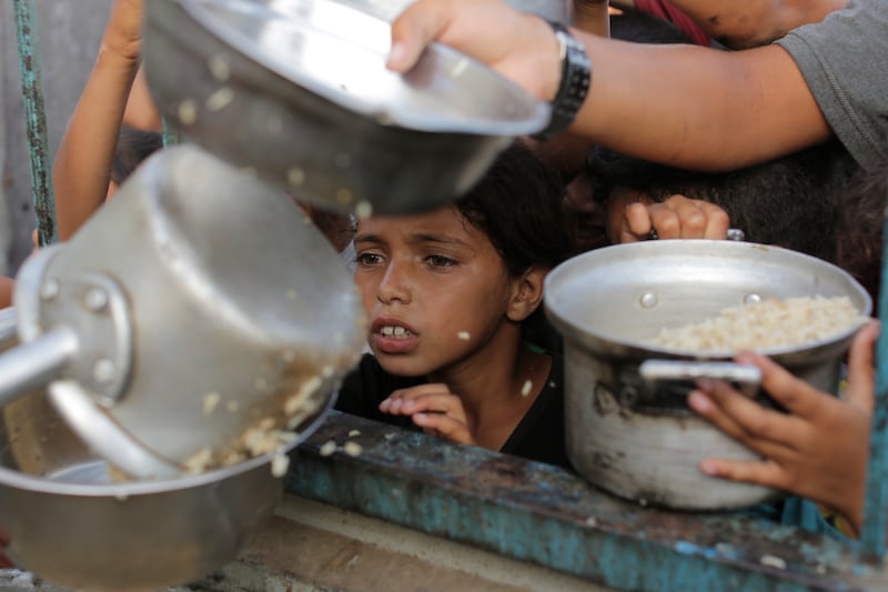A Palestinian boy receives his portion of food aid ahead of the Eid al-Adha holiday in Jerusalem (Jehad Alshrafi/AP)