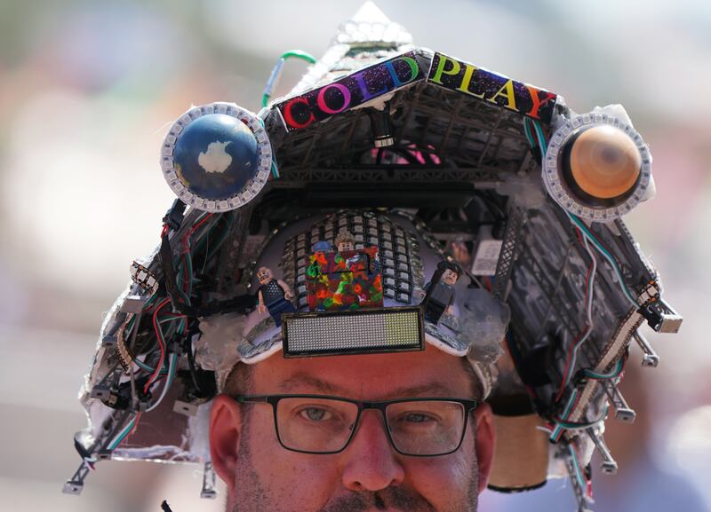 A festivalgoer wearing a Pyramid Stage Coldplay hat at the Glastonbury Festival at Worthy Farm in Somerset
