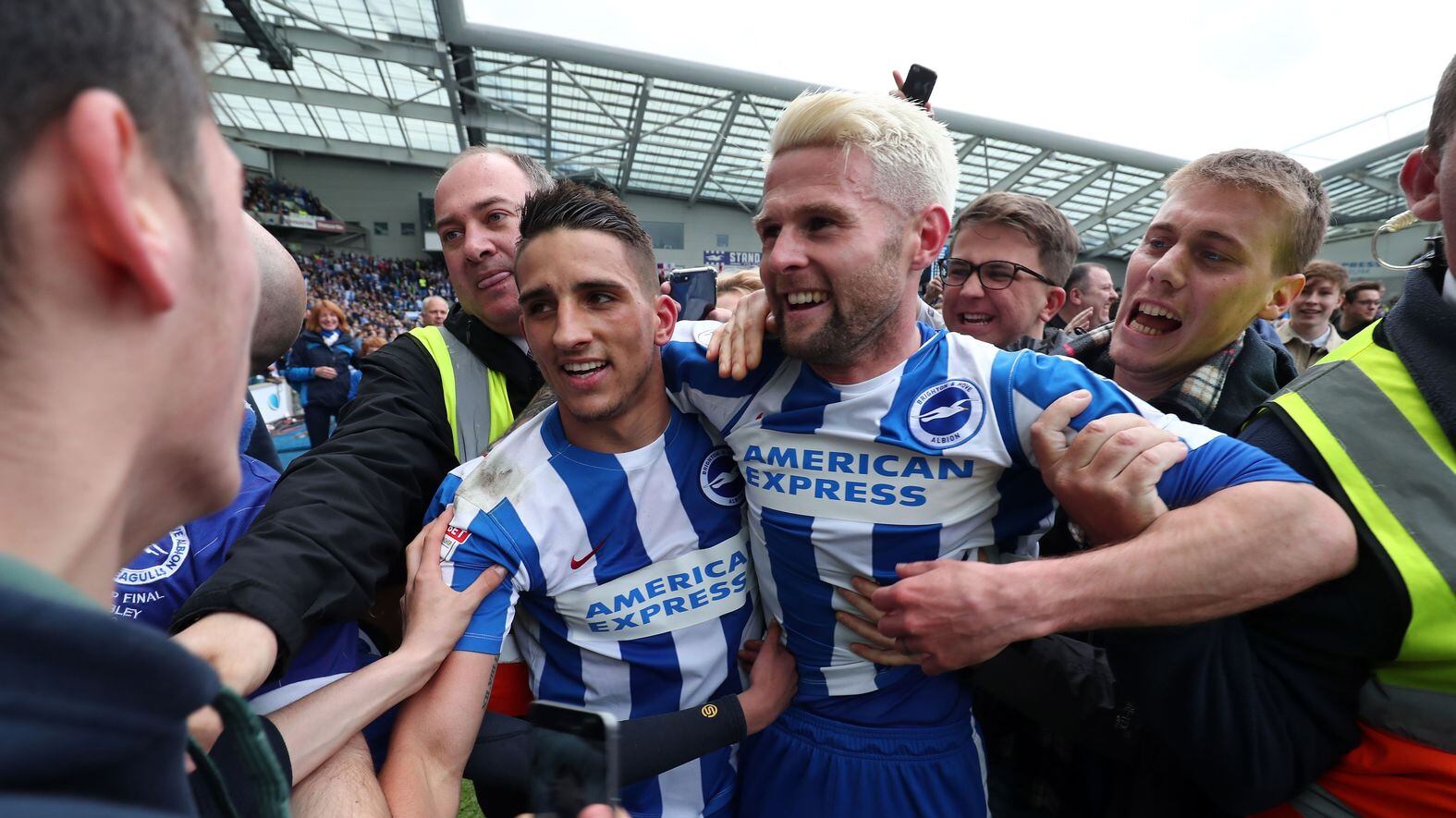 Brighton and Hove Albion's Anthony Knockaert (left) and their Northern Ireland international Oliver Norwood are mobbed by fans after helping Brighton end their 34-year exile from English soccer's top flight following their 2-1 Sky Bet Championship win over Wigan at the AMEX Stadium, Brighton on Monday April 17 2017