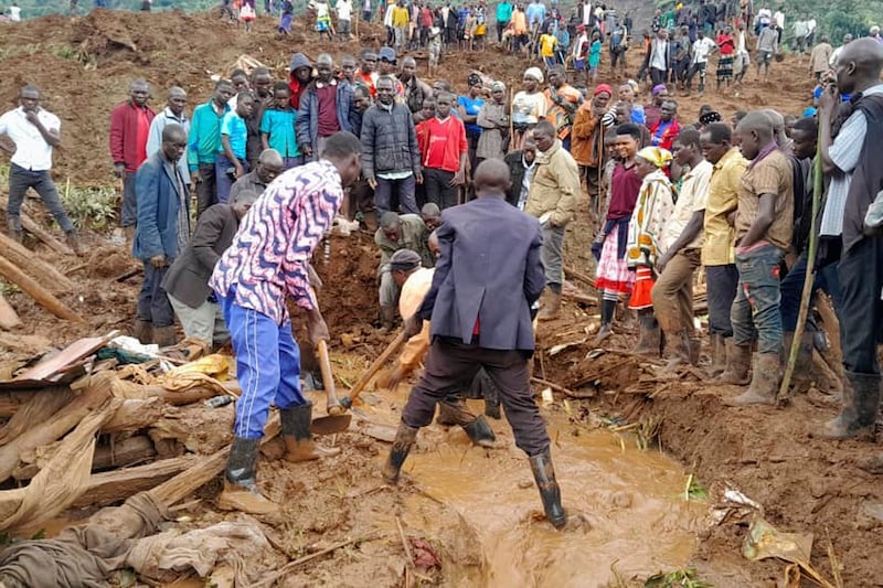 Rescue workers and people search for bodies after landslides following heavy rains buried 40 homes in the mountainous district of Bulambuli, eastern Uganda (Jean Watala/AP)