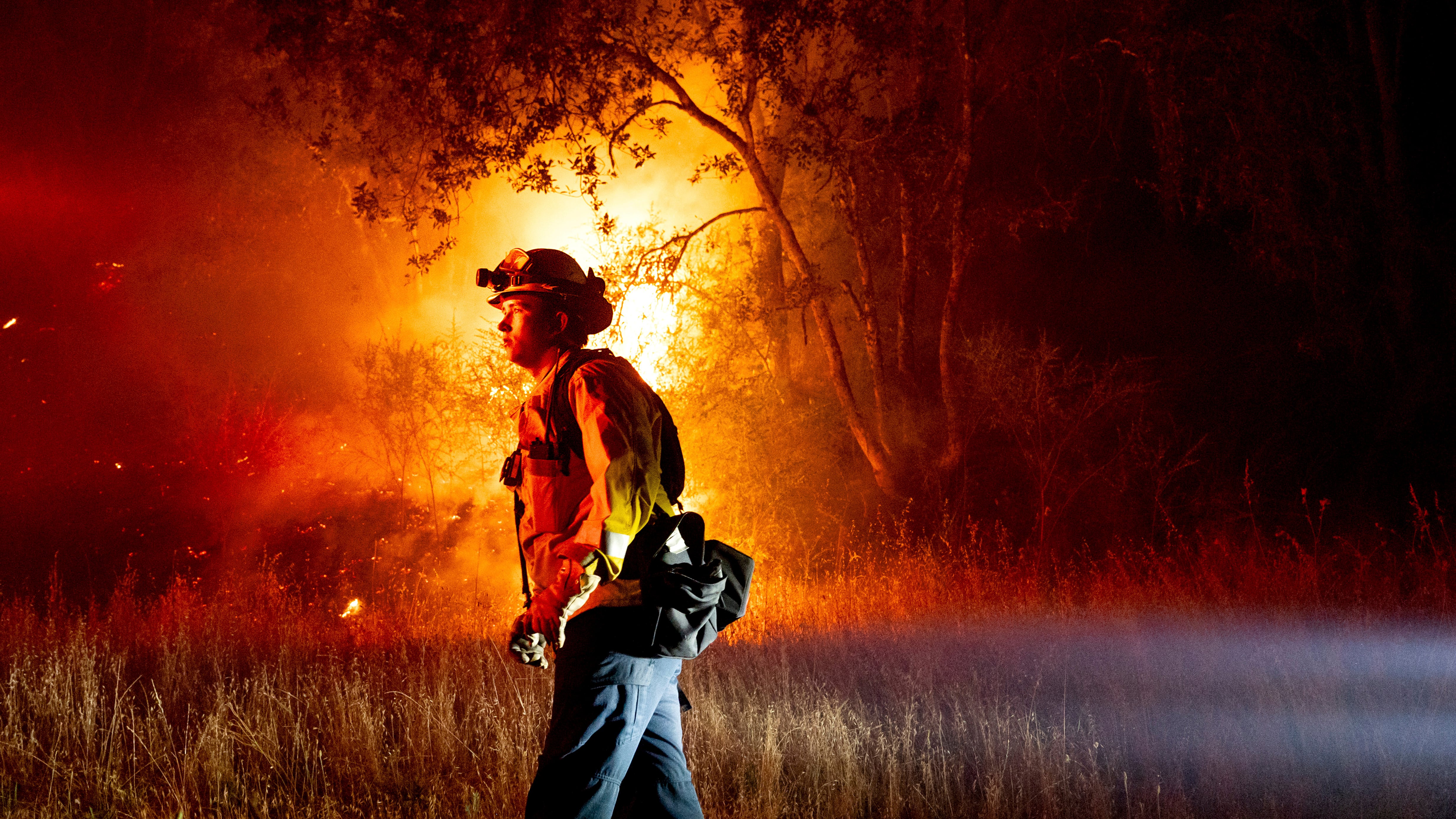 A firefighter passes flames burning along in Healdsburg, California (Noah Berger/AP)