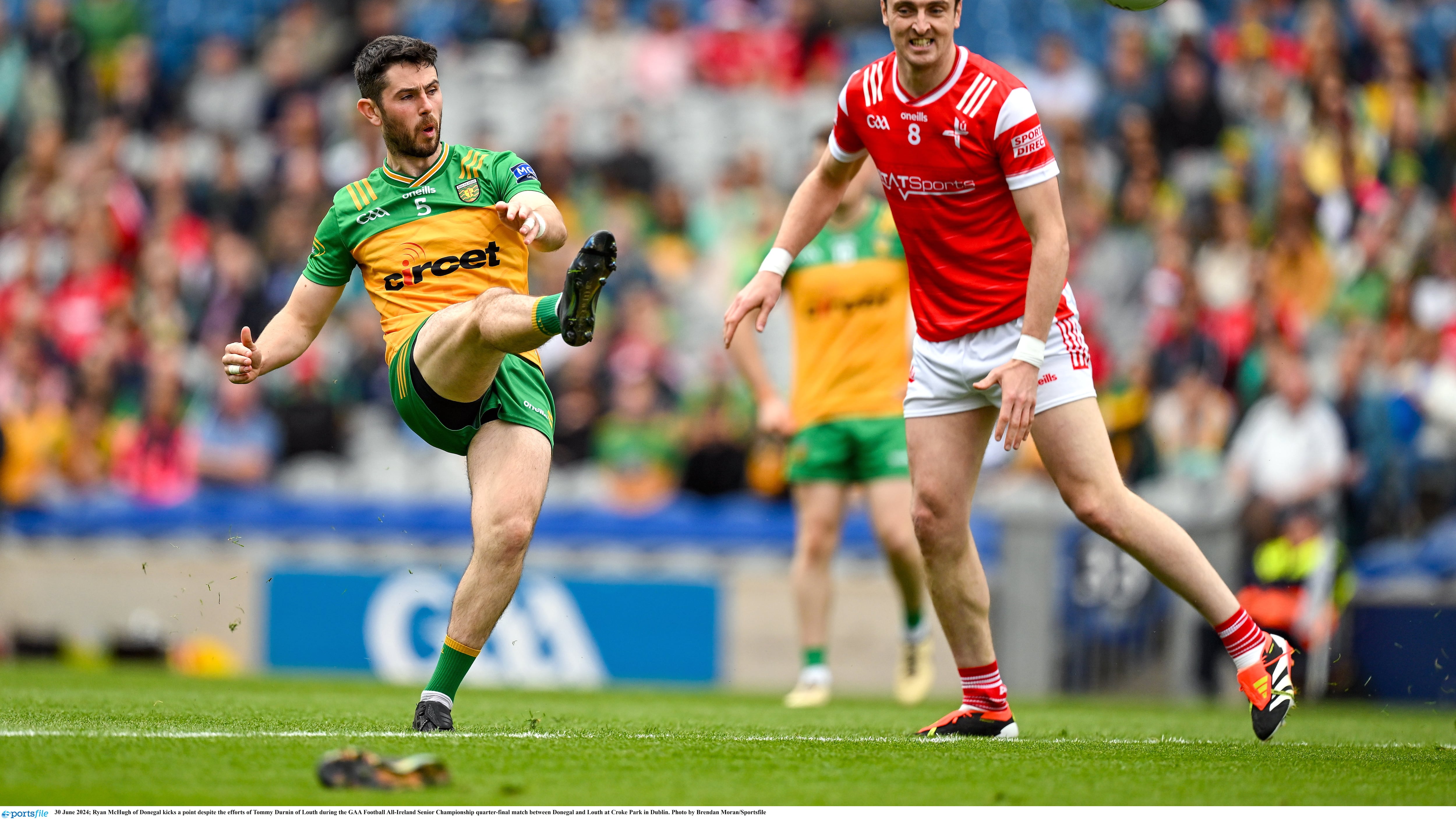 Ryan McHugh of Donegal kicks a point despite the efforts of Tommy Durnin of Louth.
