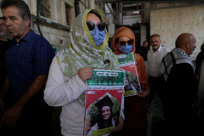 Two fellow activists of Aysenur Ezgi Eygi carry posters with her name and photo during Ms Eygi’s funeral procession in the West Bank city of Nablus (Nasser Nasser/AP)