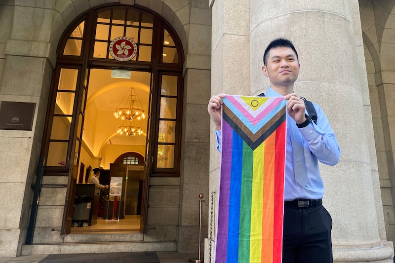 Nick Infinger, who won a lengthy legal battle over the differential treatment facing same-sex couples, holds up a rainbow banner after speaking to the media outside Hong Kong’s top court (Alice Fung/AP)