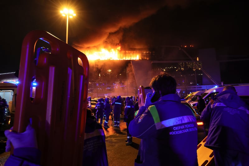 A medic stands near ambulances parked outside the burning building of Crocus City Hall (Vitaly Smolnikov/AP)