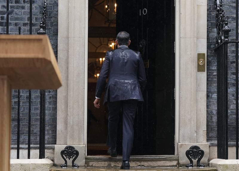 Prime Minister Rishi Sunak, soaked by rain, walks back in to 10 Downing Street after issuing a statement calling a General Election for July 4