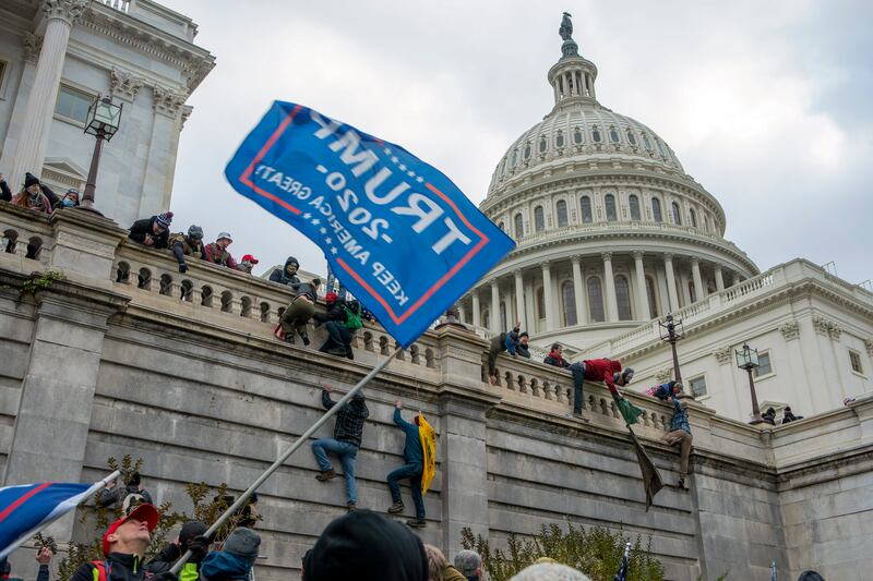 Supporters of Donald Trump climb the west wall of the US Capitol building during rioting in January 2021 (Jose Luis Magana/AP)