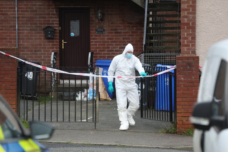 A masked police officer pictured inside a cordoned off area as forensic work is carried out