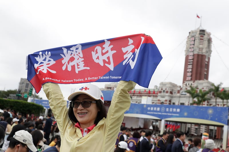 A woman poses with a banner which reads ‘Honour Time’ during National Day celebrations in front of the Presidential Building in Taipei, Taiwan (Chiang Ying-ying/AP)