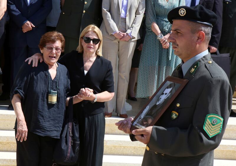 Family members watch as a soldier leads a guard of honour at the funeral service in Nicosia (Philippos Christou/AP)