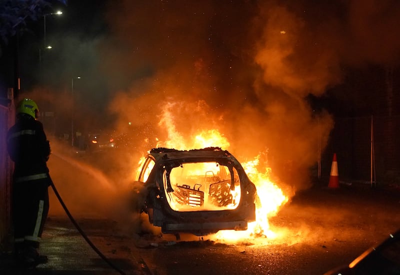 Firefighters tend to a burning police car as officers are deployed on the streets of Hartlepool following a violent protest