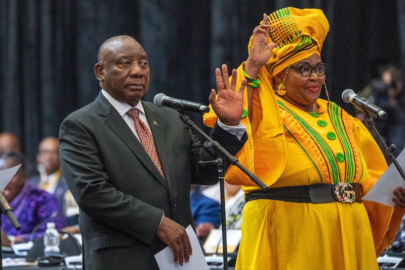 Cyril Ramaphosa raises his hand as he is sworn is as a member of parliament, with Pemmy Majodina, an ANC politician (Jerome Delay/AP)